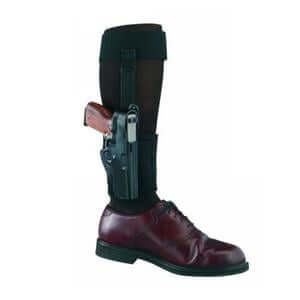 Ankle holster featuring a handgun secured under a black strap, paired with a polished dress shoe.