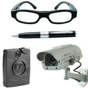 A collection of security items including glasses, a pen, a body camera, and a surveillance camera.