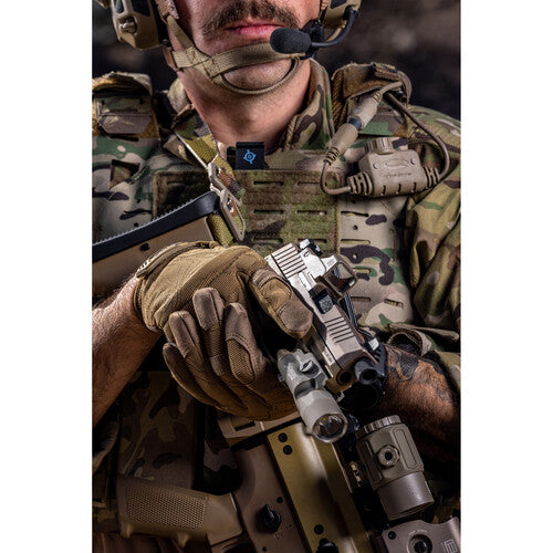 Soldier in tactical gear holding a pistol with mounted tactical light, showcasing military readiness and precision equipment.