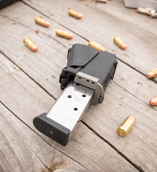 Black gun magazine on a wooden surface with bullets around