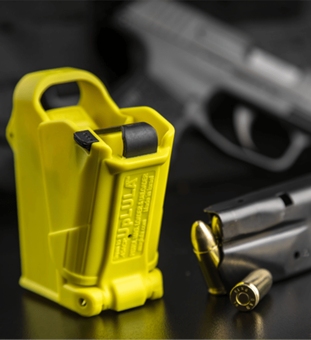 Yellow gun magazine loader with a blurred gun and bullets in the background