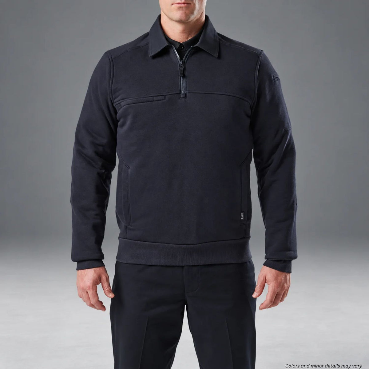 Man wearing a dark navy 5.11 long-sleeve job shirt with a quarter-zip front, collar, ribbed cuffs, and side pockets against a gray studio background.