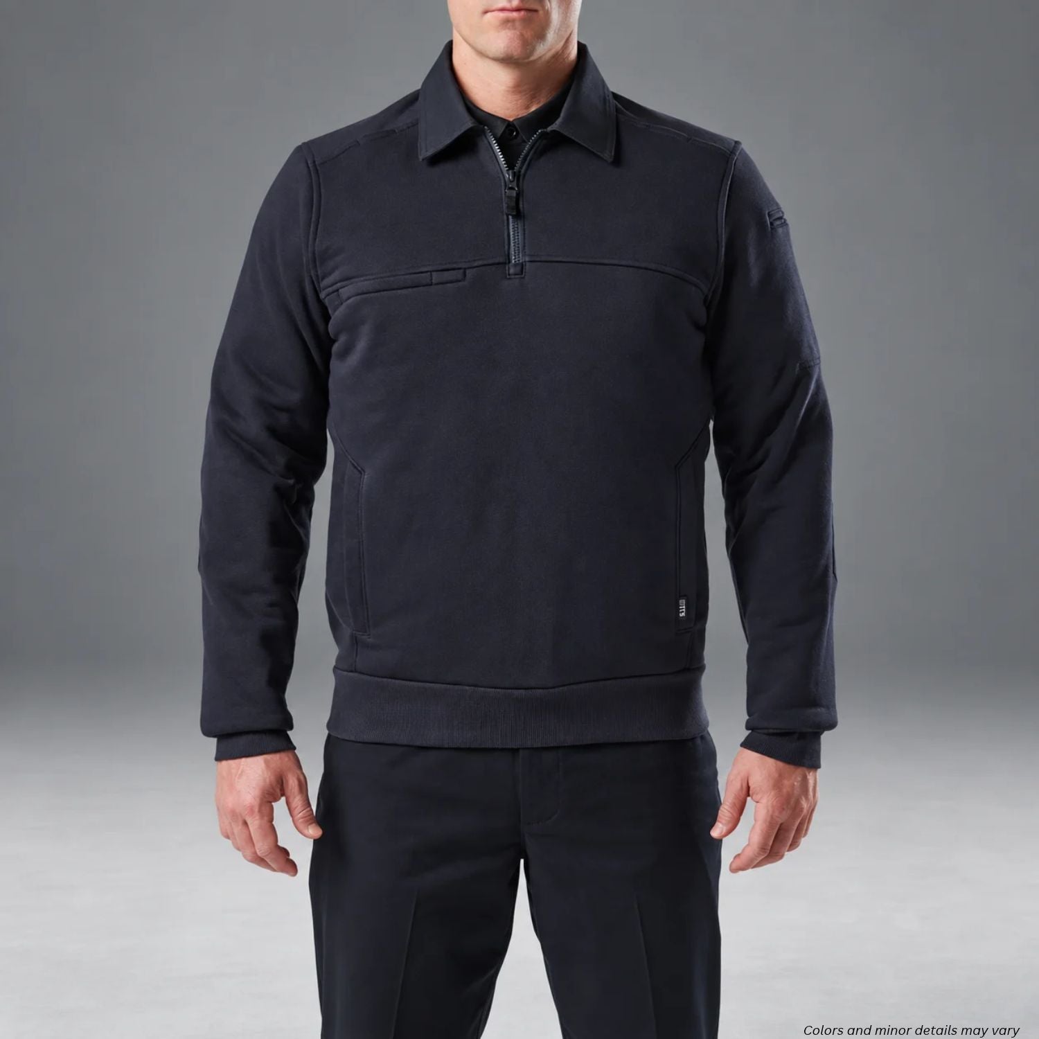 Man wearing a dark navy 5.11 long-sleeve job shirt with a quarter-zip front, collar, ribbed cuffs, and side pockets against a gray studio background.