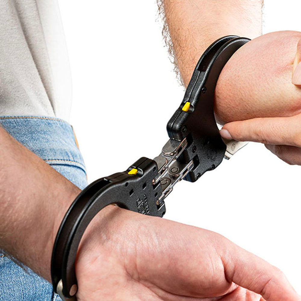 Handcuffs being applied to a wrist with a neutral background