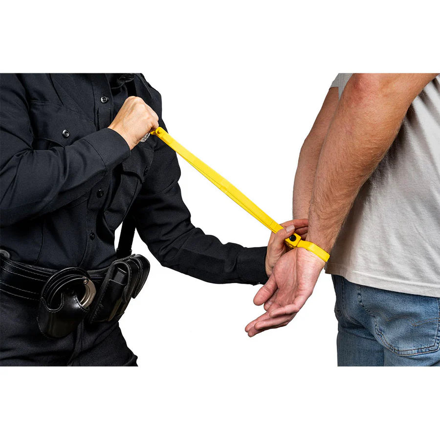 Person in black uniform holding a yellow restraint device to another person's wrist.