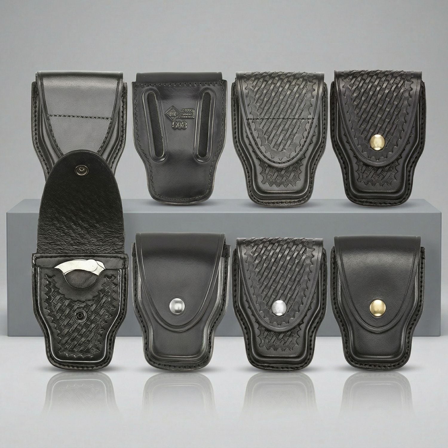 Set of black leather handcuff holsters with metallic clasps on a gray background