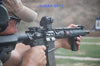 User aiming a rifle equipped with a vertical grip at a shooting range, showcasing precision and control in practice.