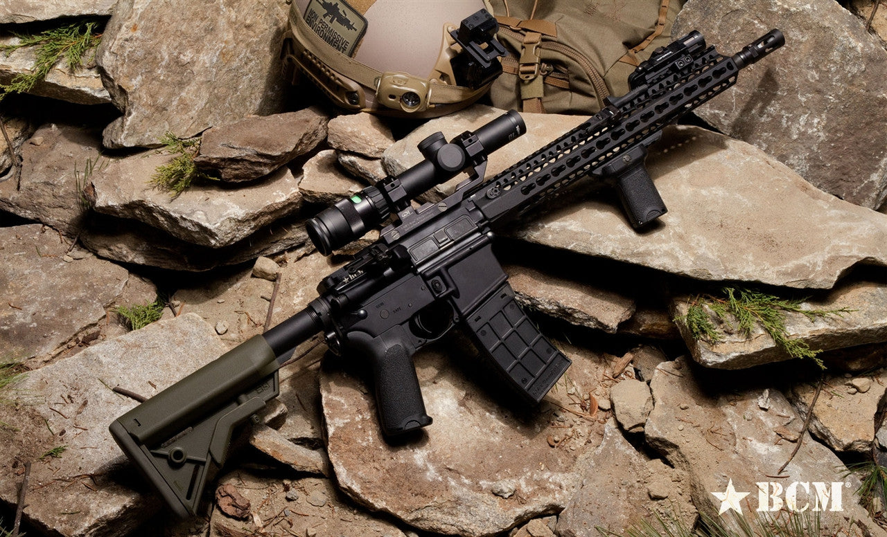 BCM rifle with vertical grip and scope on rocky terrain, showcasing tactical accessories and design features.