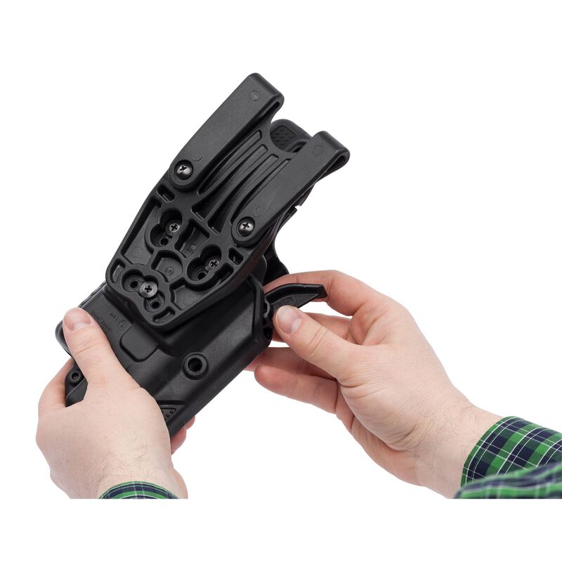 Black tactical holster held by a person on a white background
