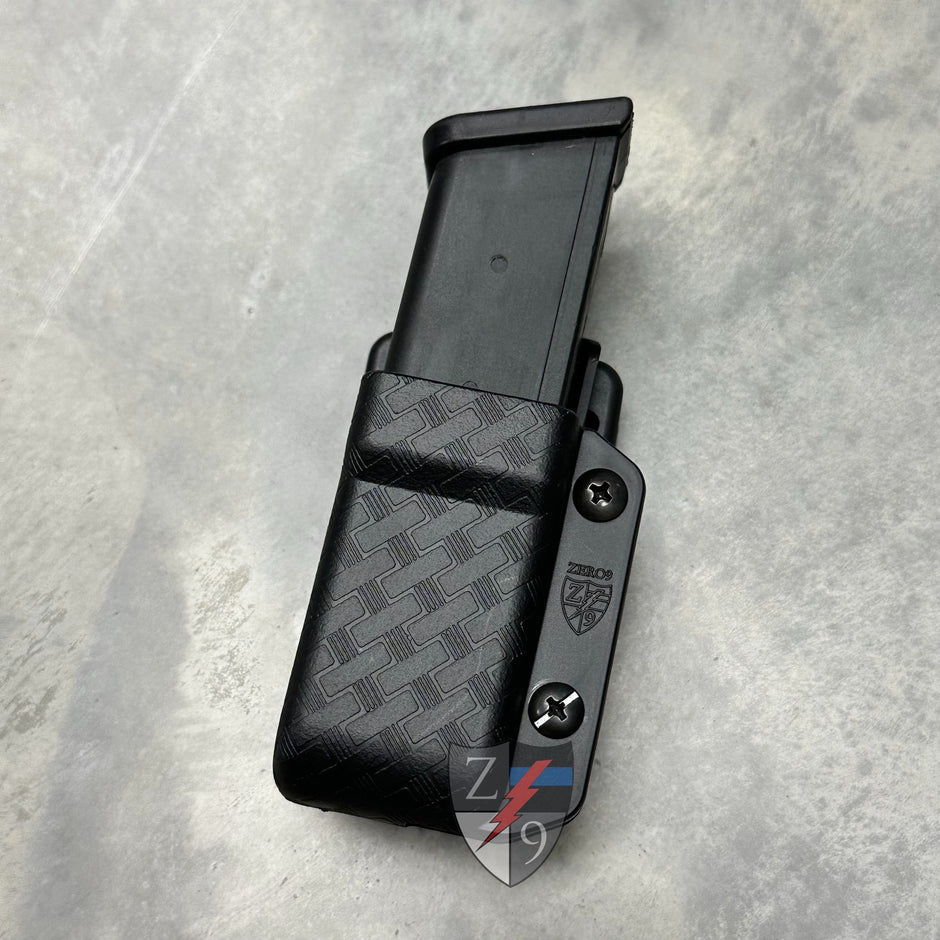 Black magazine holster with a patterned design on a gray surface