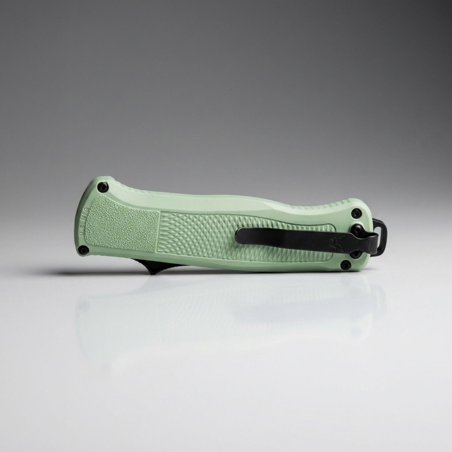 Green folding knife on a gray background