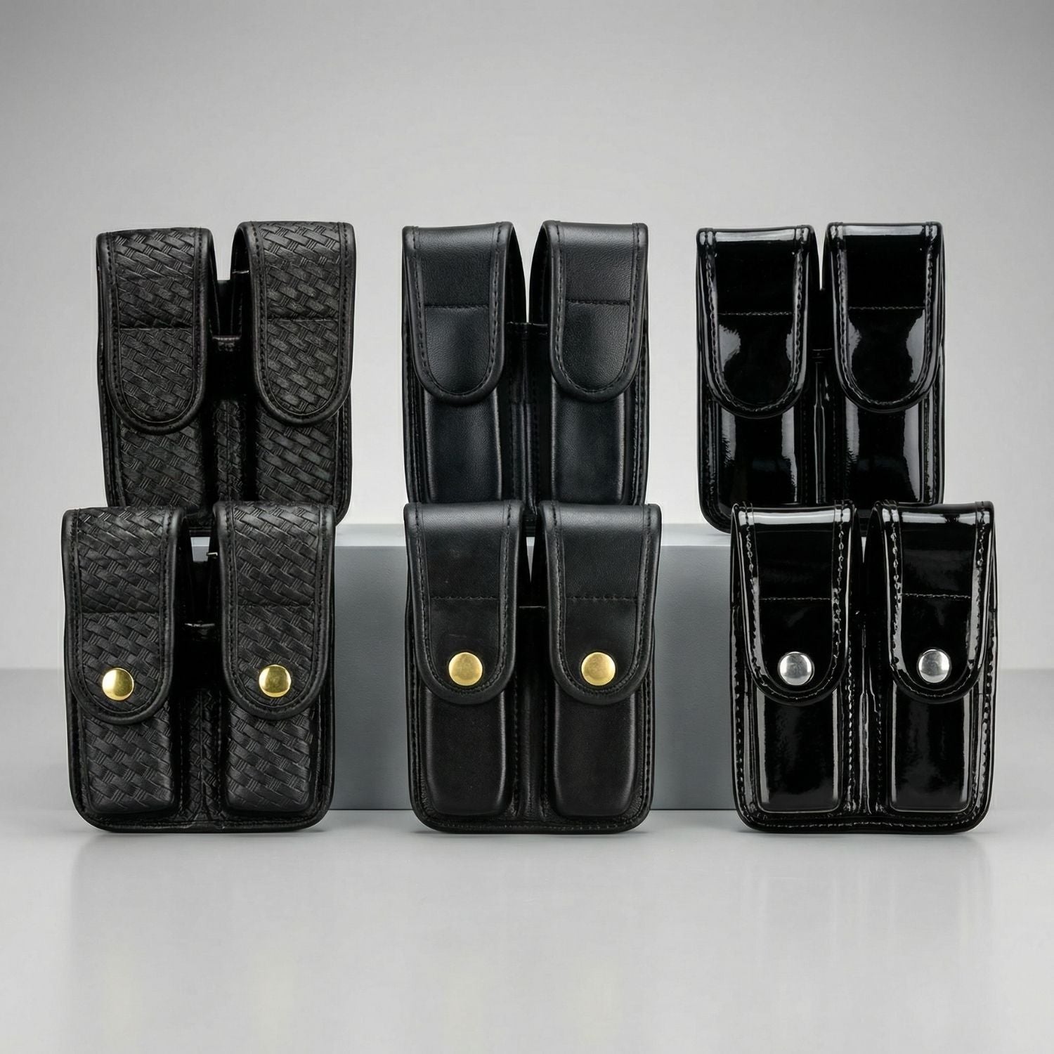 Set of black leather pouches with gold buttons on a gray background