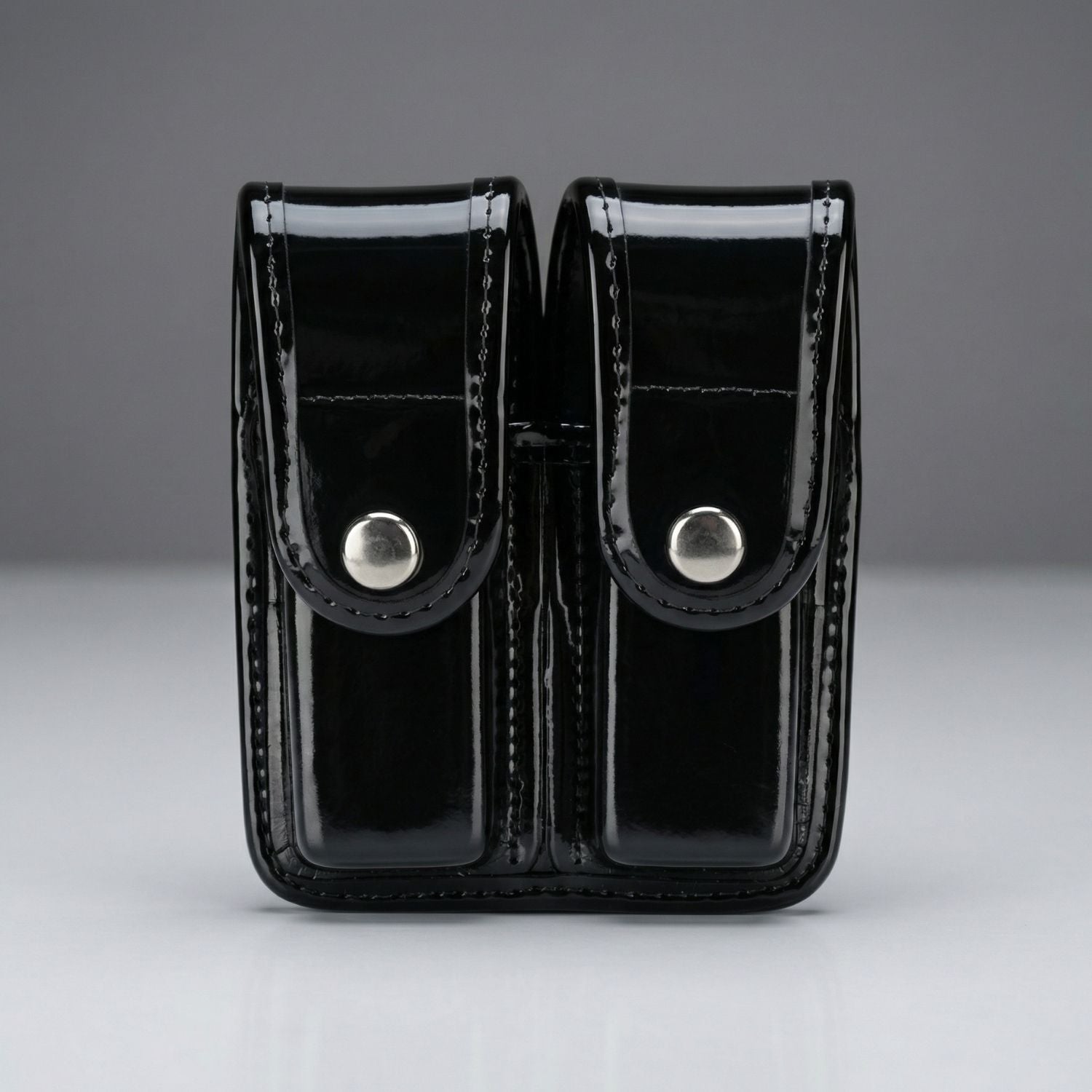 Black patent leather double magazine holder on a gray background