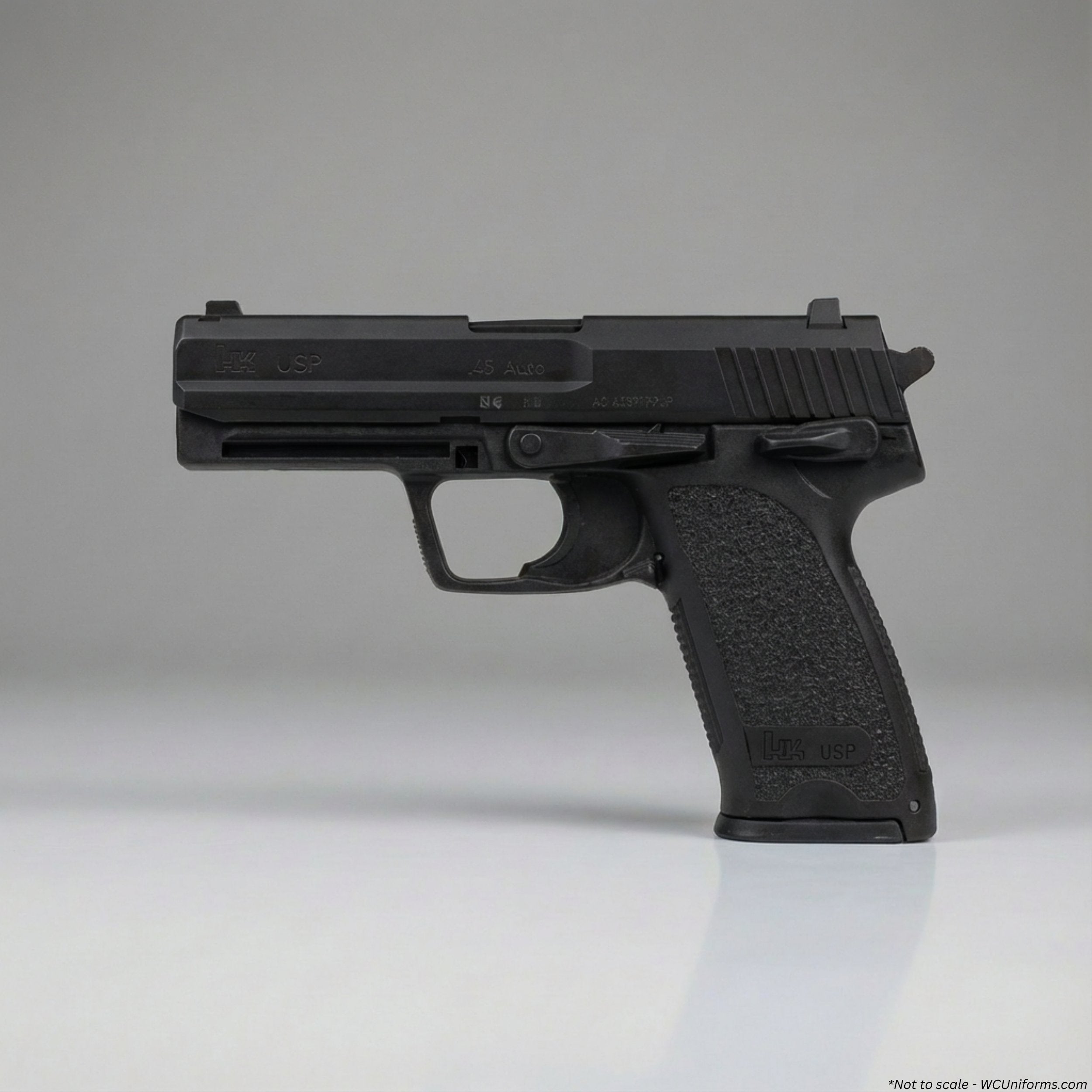 Black plastic training handgun on a reflective surface with a gray background