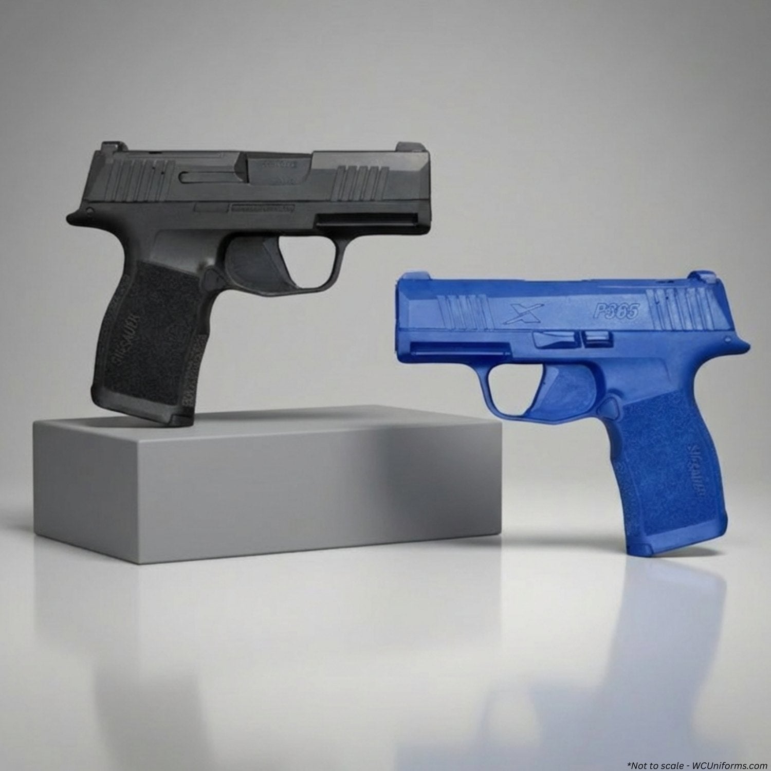 Black gun on a gray block and blue gun on a white surface with a gray background