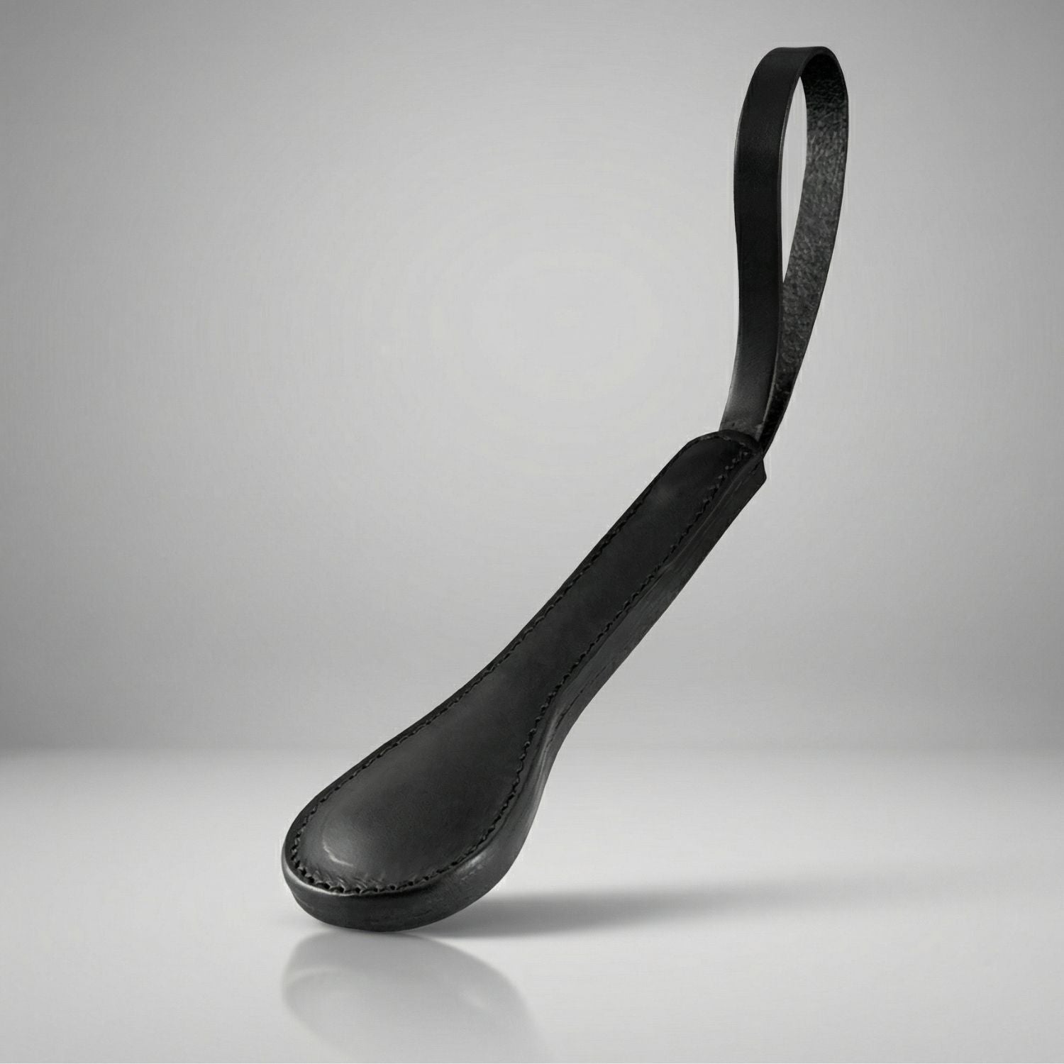 Black leather sap with a strap on a gray background
