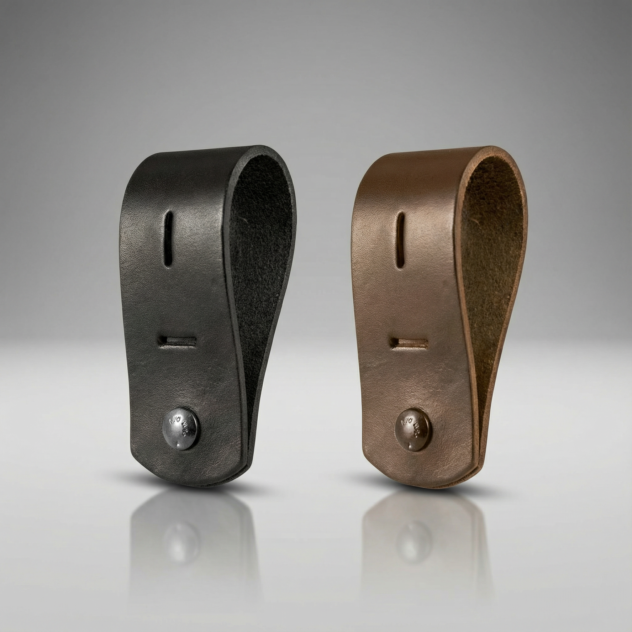 Two leather Boston Leather K9 Badge Holder 8501, one black and one bronze, on a reflective surface with a gray background.