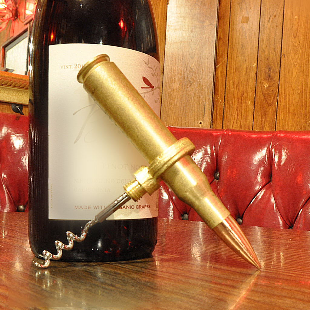 Wine bottle with a unique corkscrew shaped like a bullet on a wooden table.