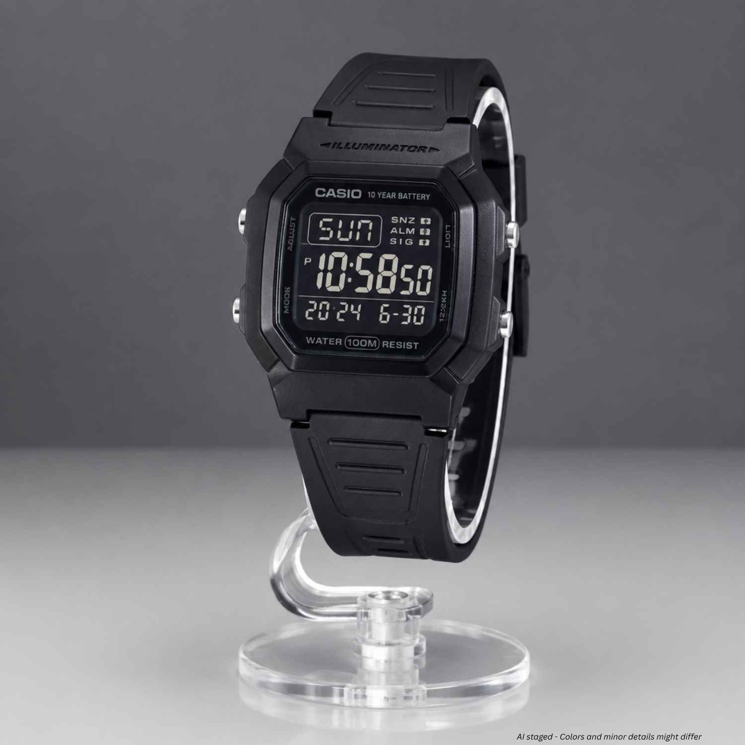 A black Casio digital wristwatch with a matching black strap, displayed upright on a clear acrylic stand against a dark gray studio background.
