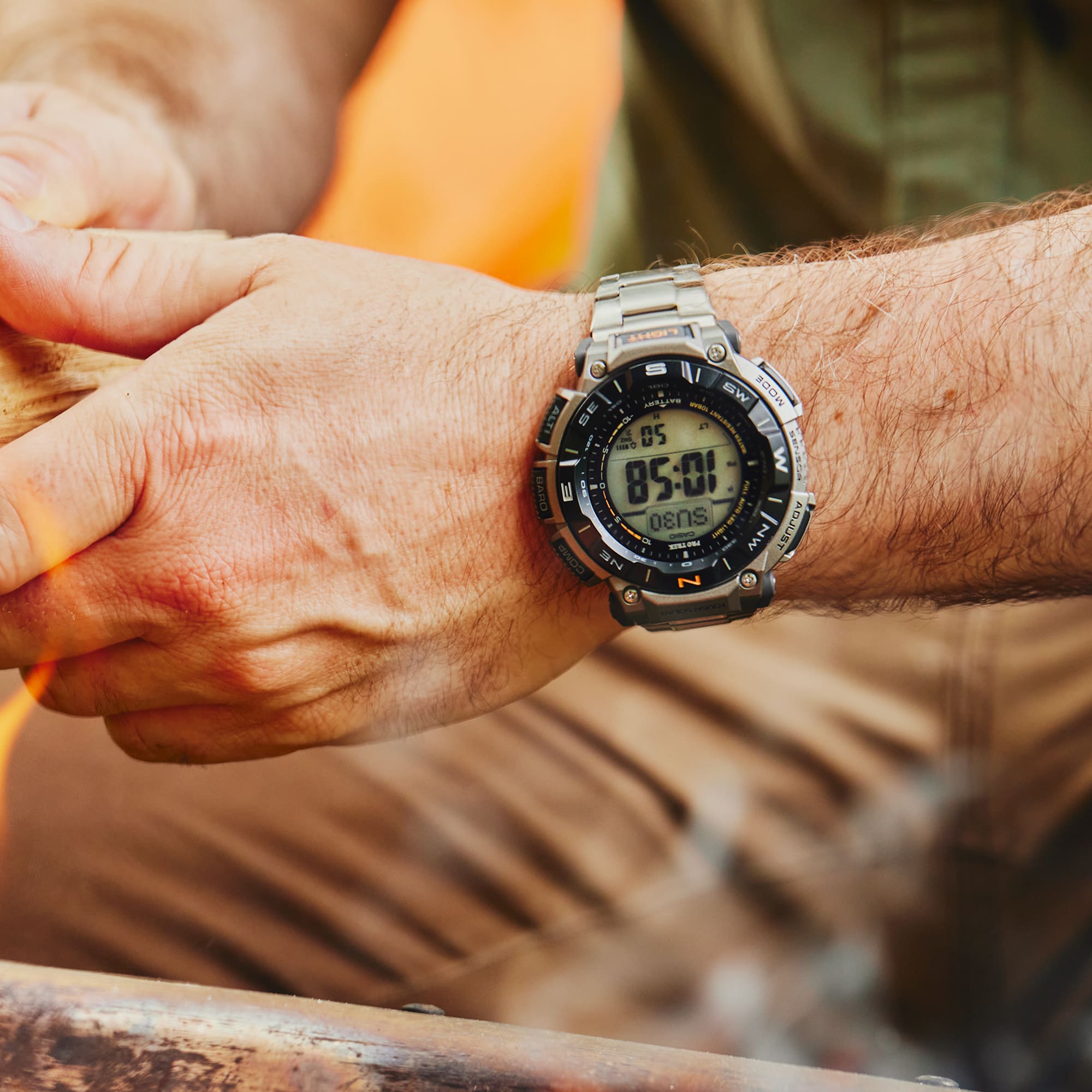 Close-up of a person's wrist wearing a digital watch with a blurred outdoor background