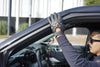 Police officer wearing gloves and sitting inside a police car with a blurred background
