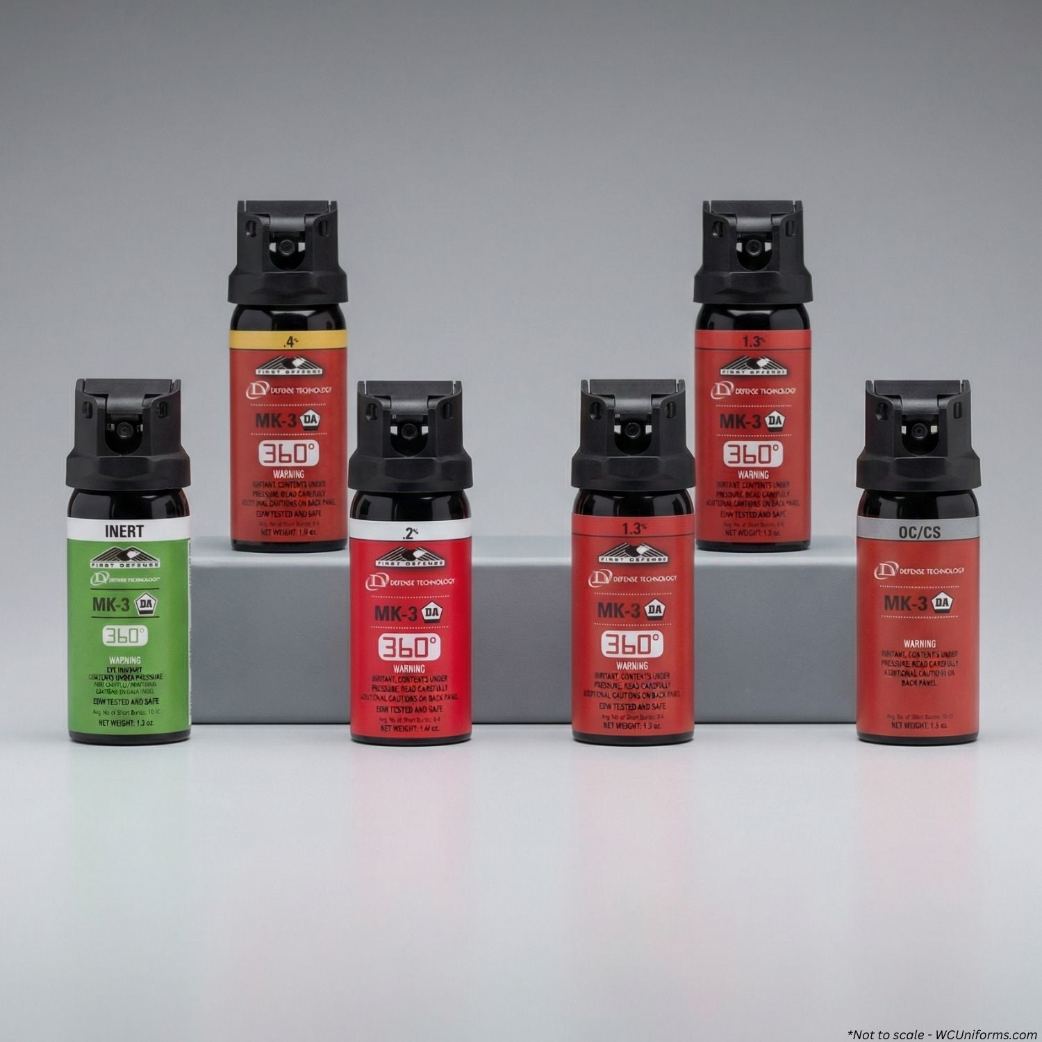 Collection of pepper spray cans with different colors and labels on a gray background