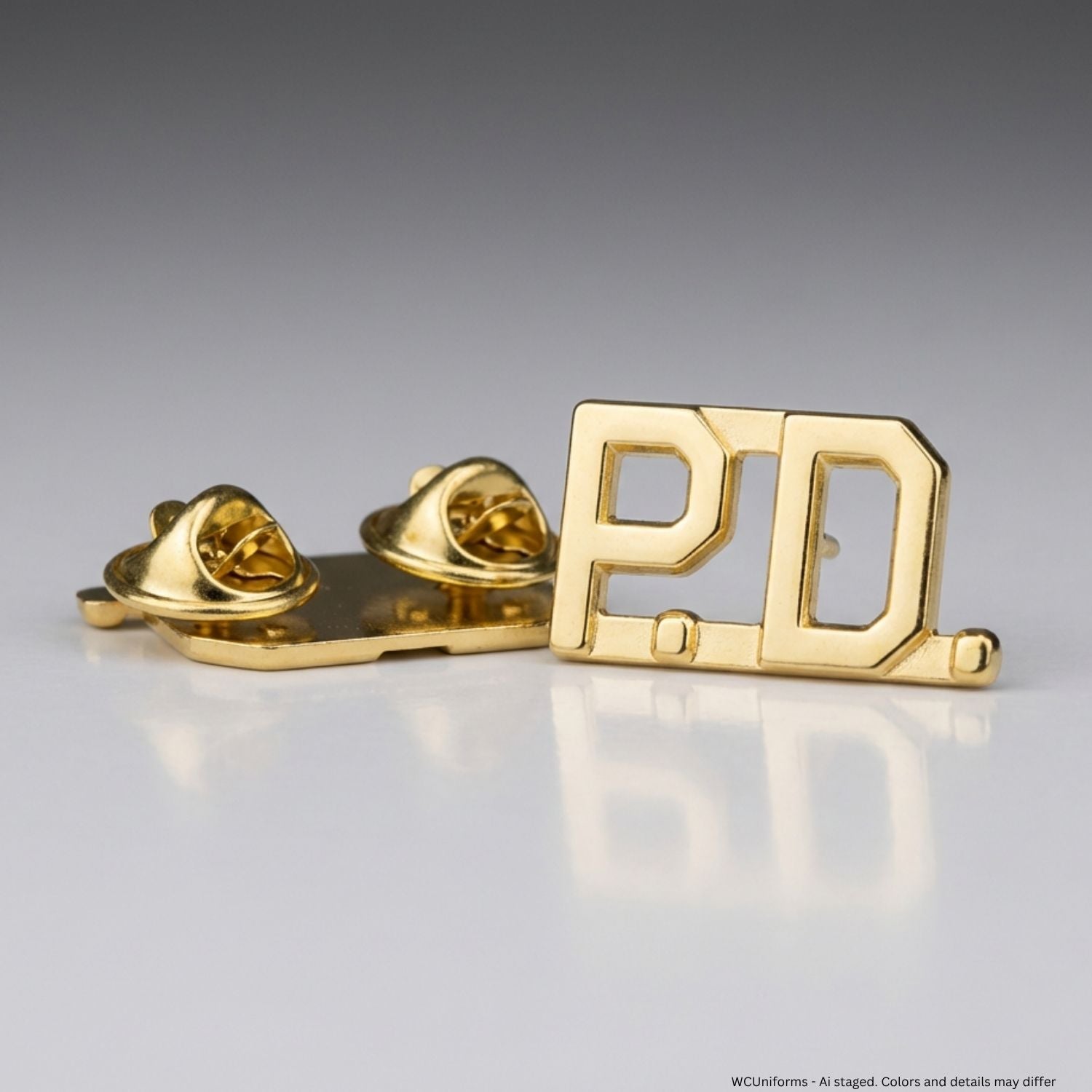 Gold 'P.D.' collar pins on a reflective surface with a gray background