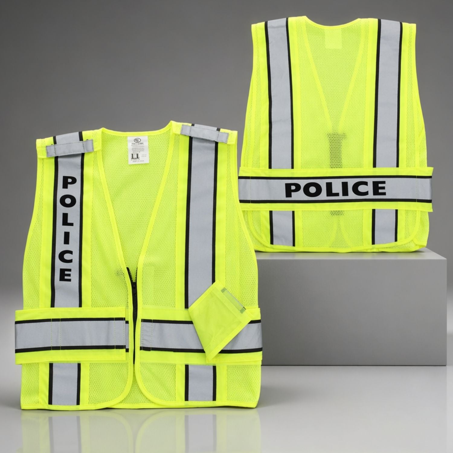 Two yellow police vests with reflective stripes on a gray background