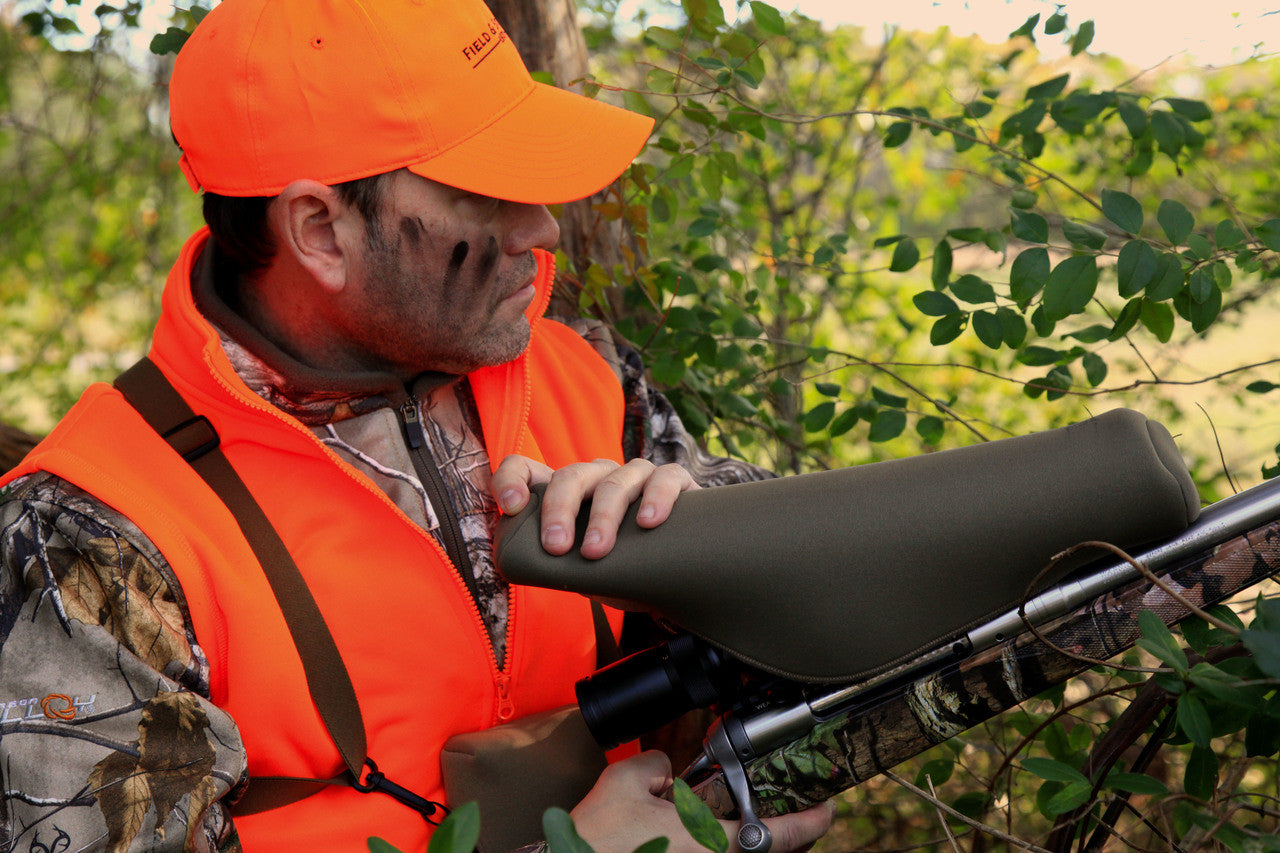 Man in hunting gear holding a rifle in a forest setting