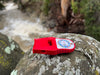 Red whistle with a keychain on a rock by a stream