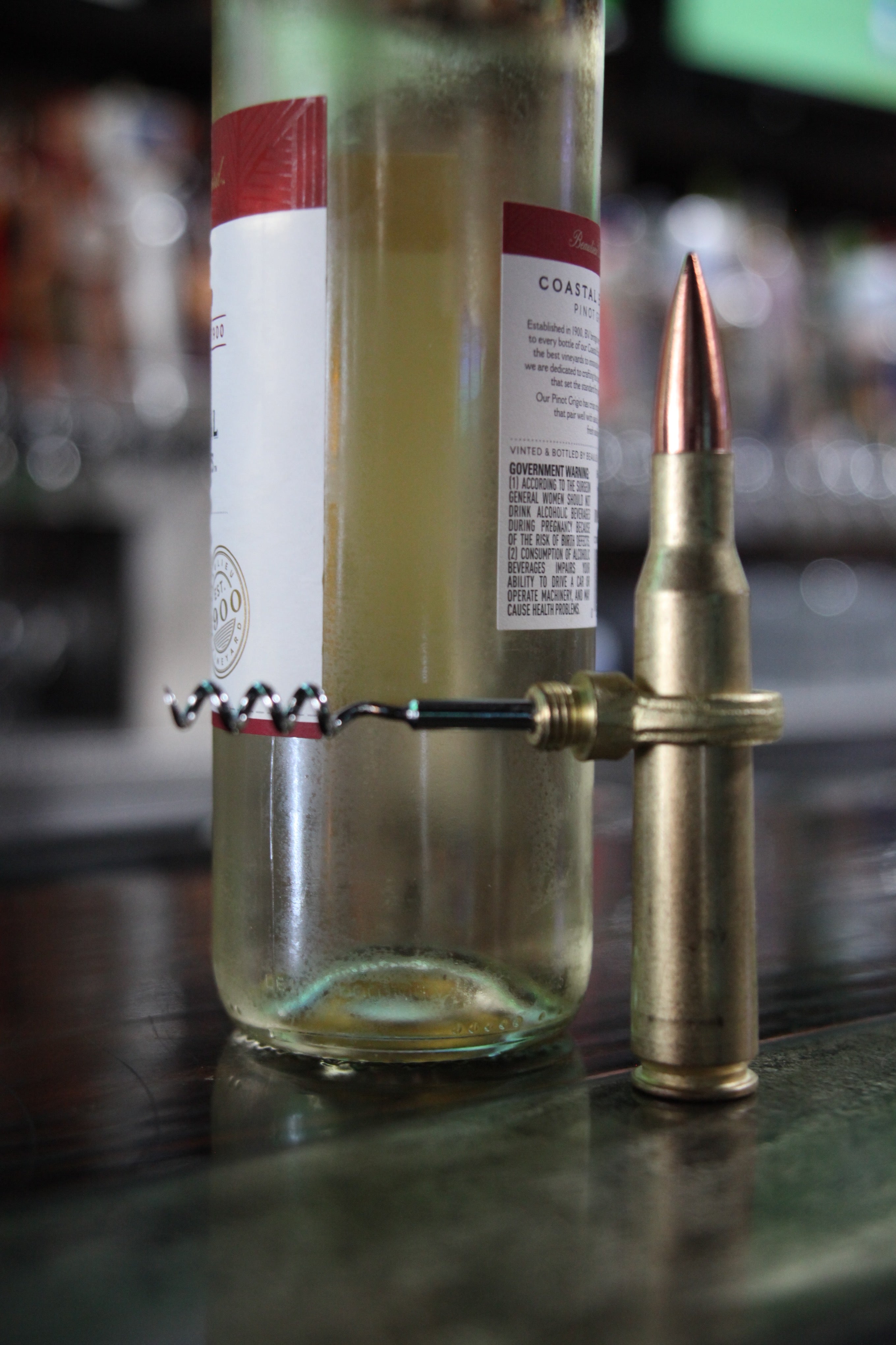 Bottle with a brass bullet-shaped bottle opener on a bar counter