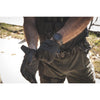 Person wearing tactical gear with a watch on a blurred natural background