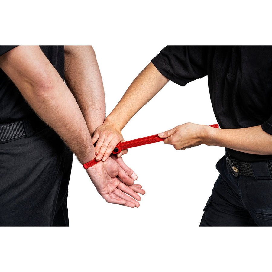 A person applying red training disposable handcuffs on another person against a white background
