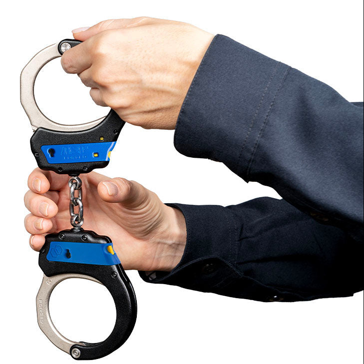 Handcuffs held by a person against a white background