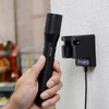 Nite Ize INOVA T4R Powerswitch tactical flashlight charging on wall mount with hand holding flashlight.