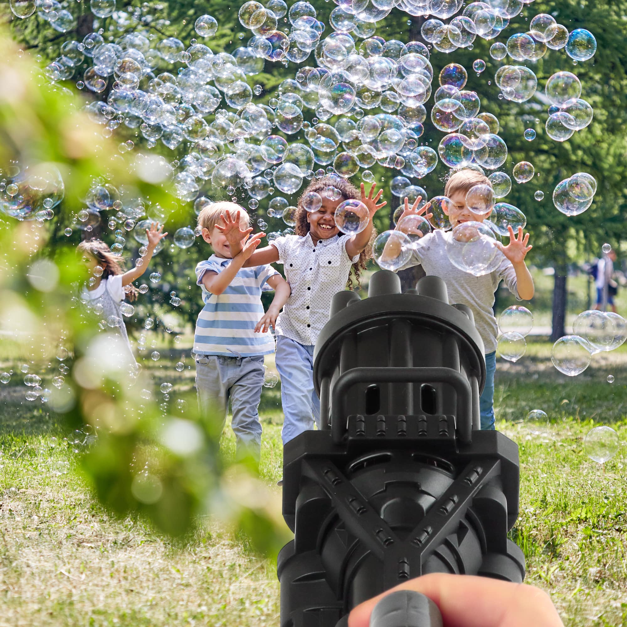 Children playing with a bubble gun in a park
