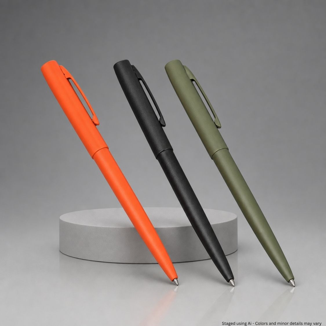 Three pens in orange, black, and green on a gray background