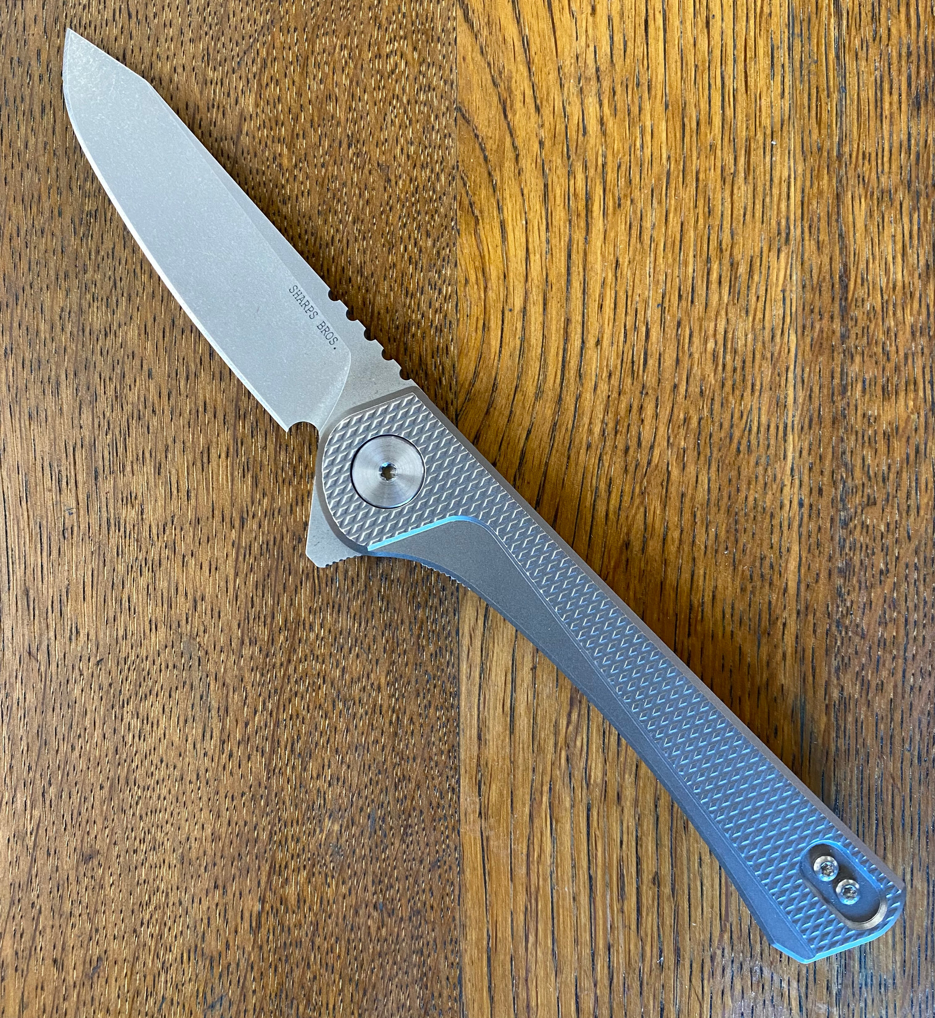 Sharps Bros Meanstreak folding knife with CPM MagnaCut blade on wooden surface, showcasing sleek design and craftsmanship.