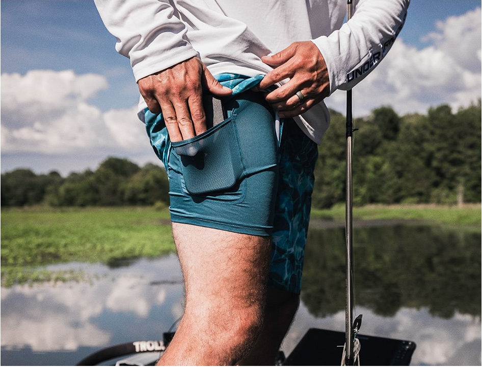 Person fishing on a boat with green shorts and a white shirt.