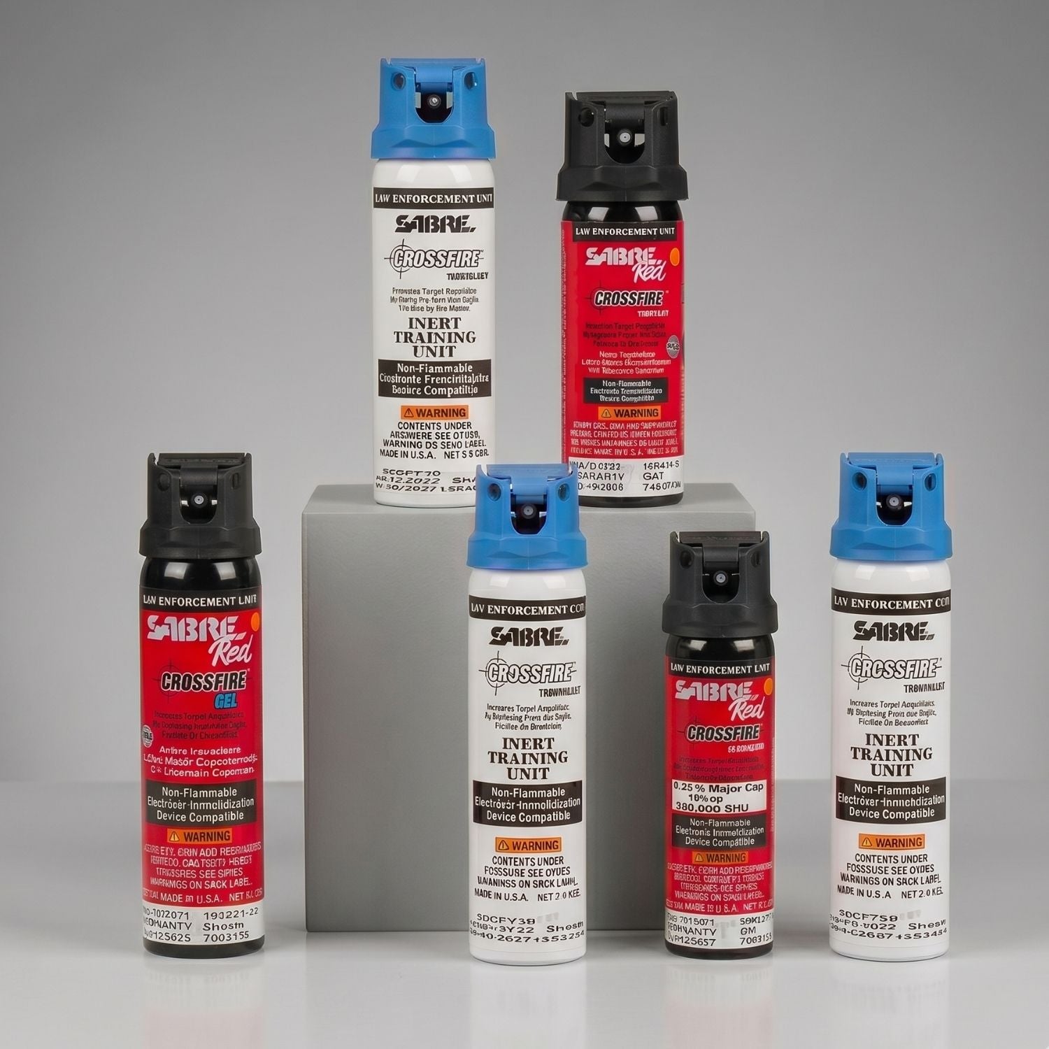 Collection of Sabre Red Crossfire pepper spray cans on a gray background