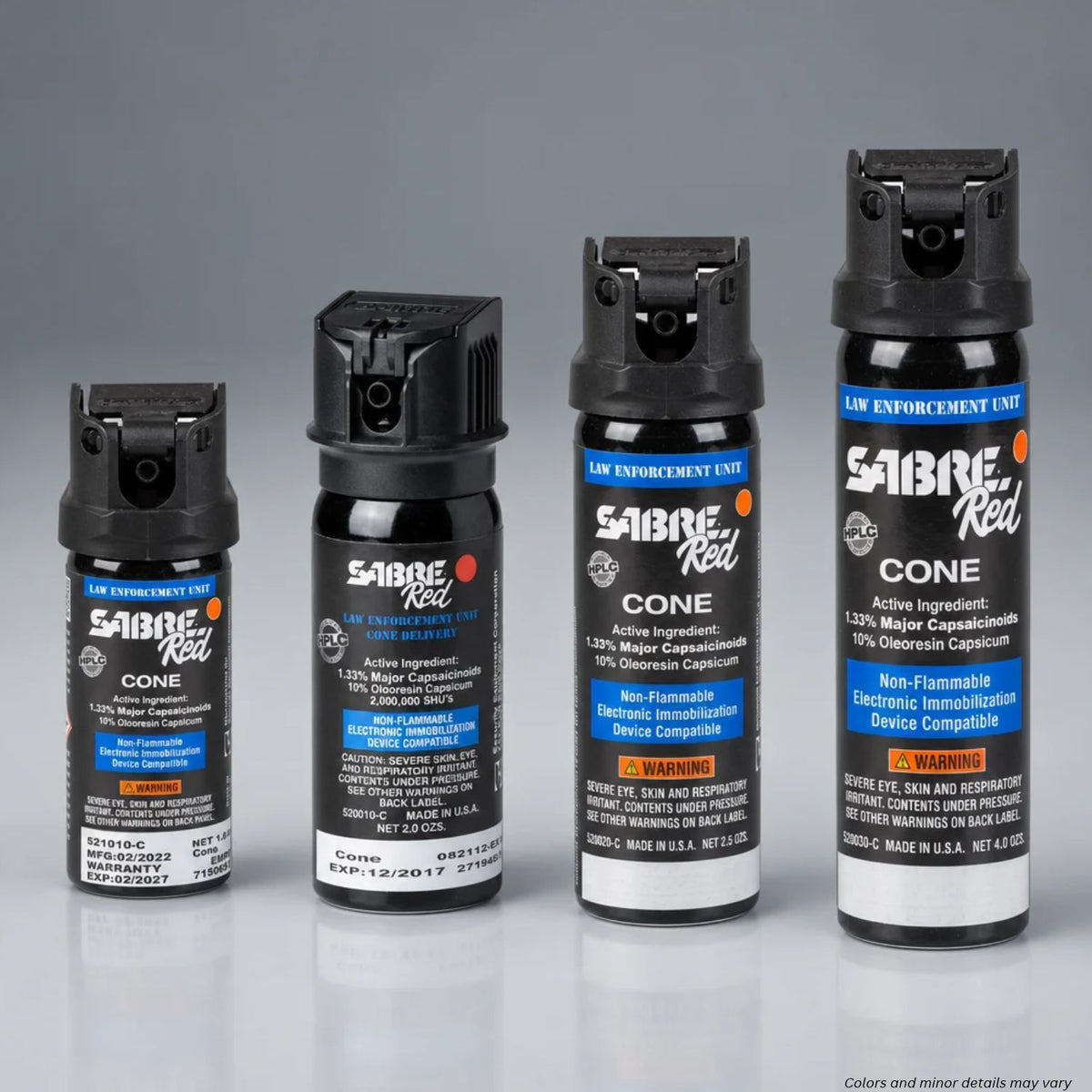 Four Sabre Red pepper spray canisters in different sizes arranged in ascending order from left to right on a reflective gray surface against a gradient gray background.