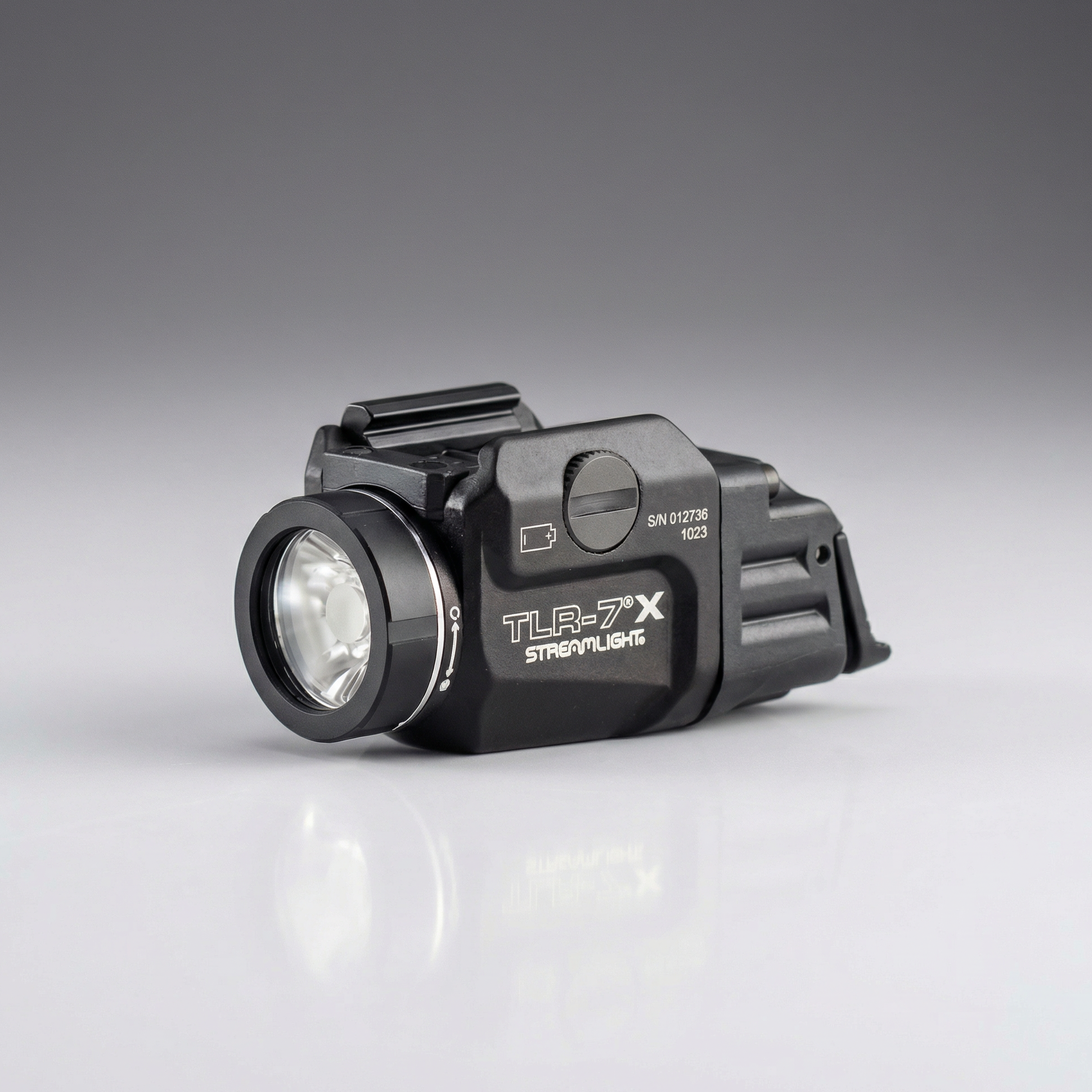 Black tactical flashlight with 'TLR-7X' branding on a gray background