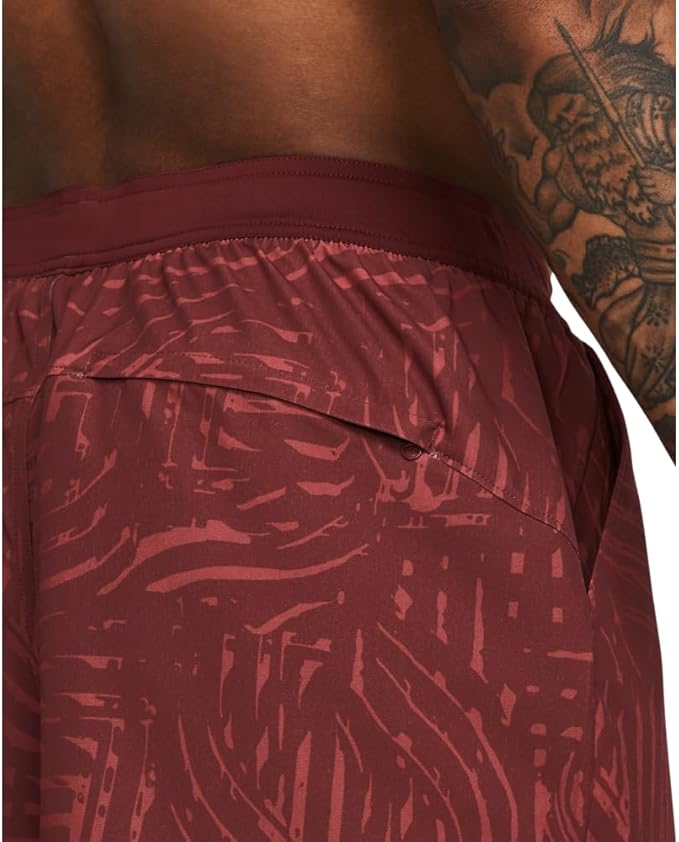 Maroon athletic shorts with a geometric pattern worn by a person with tattoos.