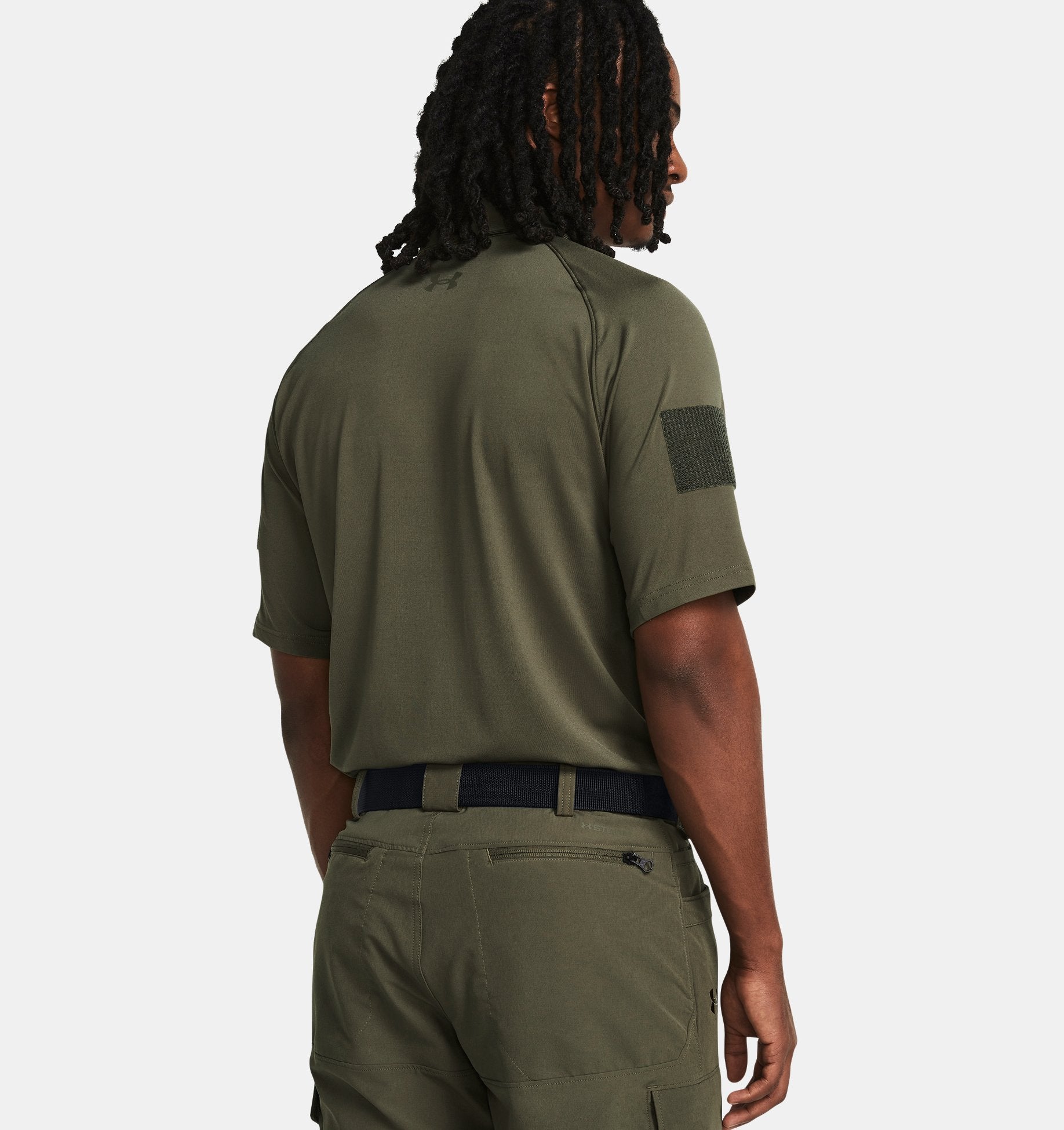 Back view of a man wearing an olive green Under Armour UA Tac Elite Polo, showcasing its tactical design and breathable fabric.