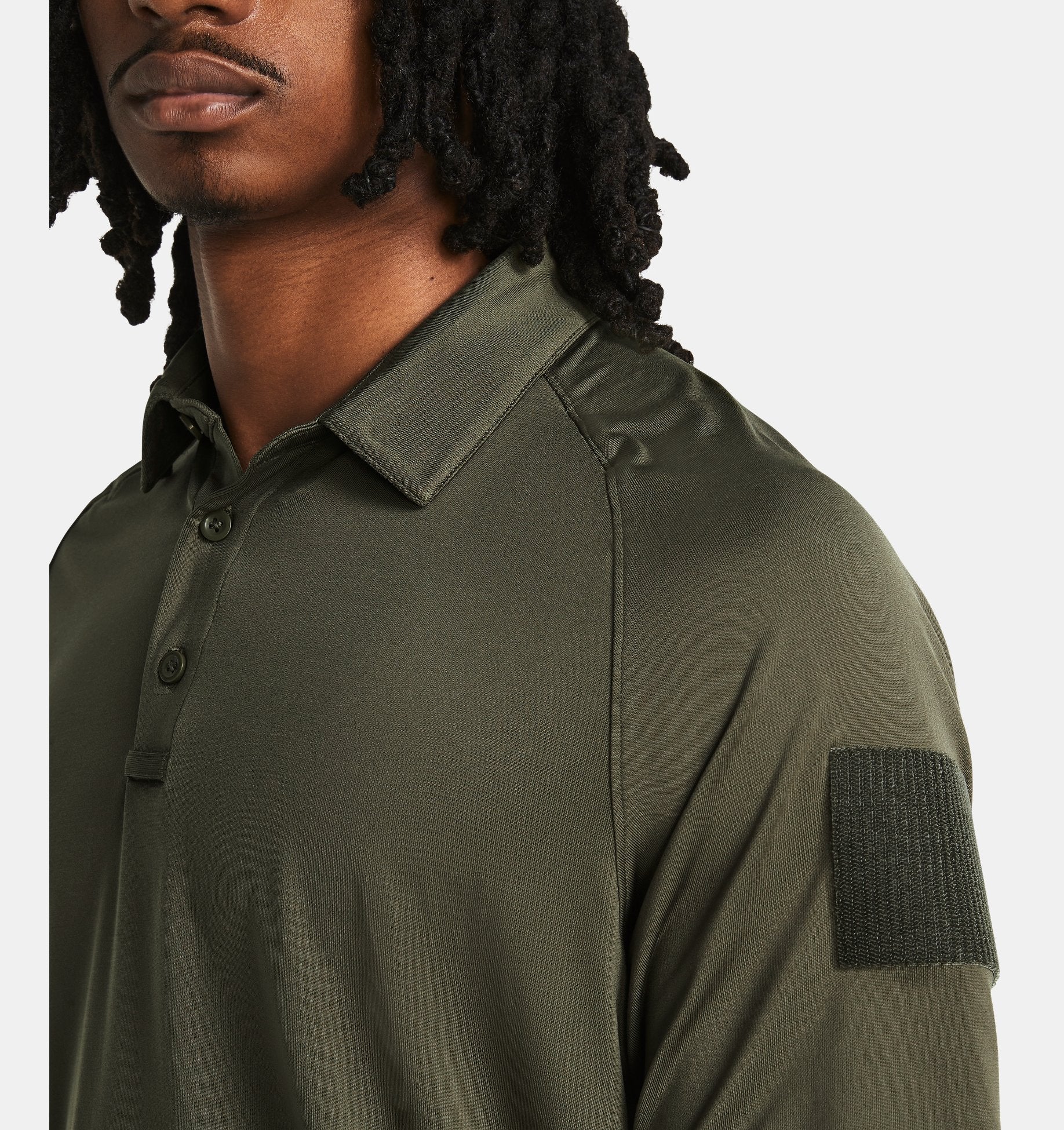 Model wearing Under Armour Men's UA Tac Elite Polo, featuring a breathable fabric and tactical design in olive green.