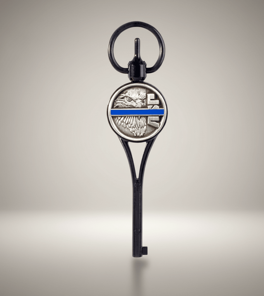 Key-shaped keychain with an eagle emblem and thin blue line on a beige background