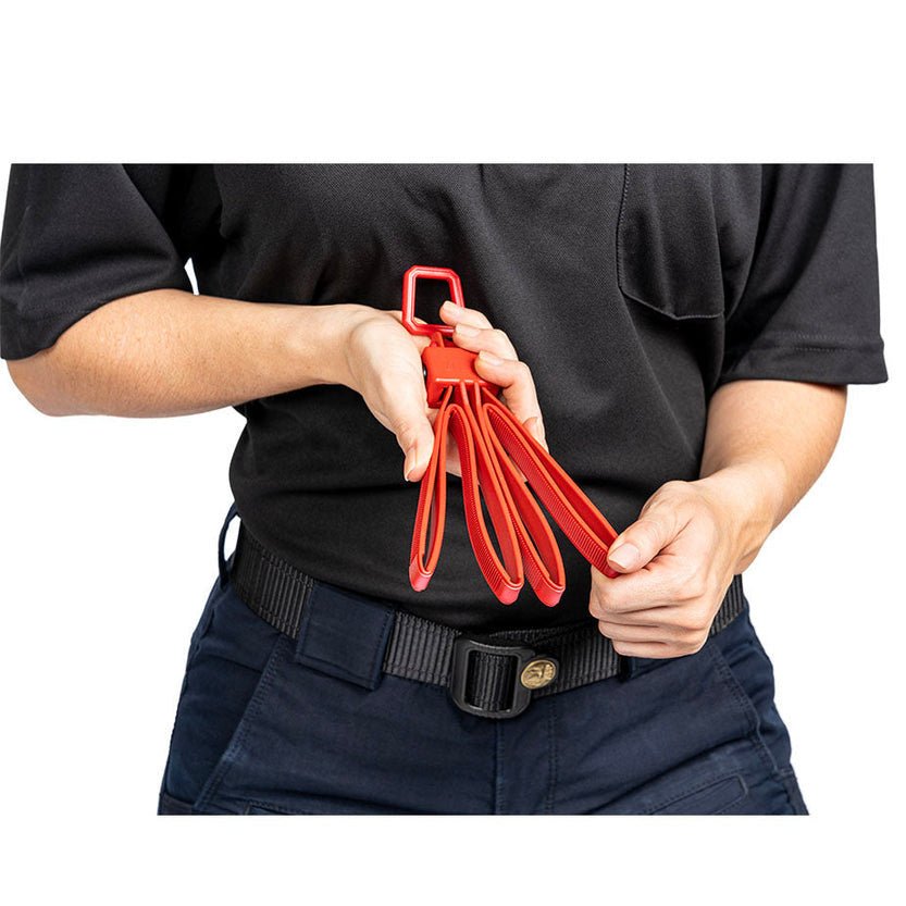 Person holding a set of red training handcuffs against a white background