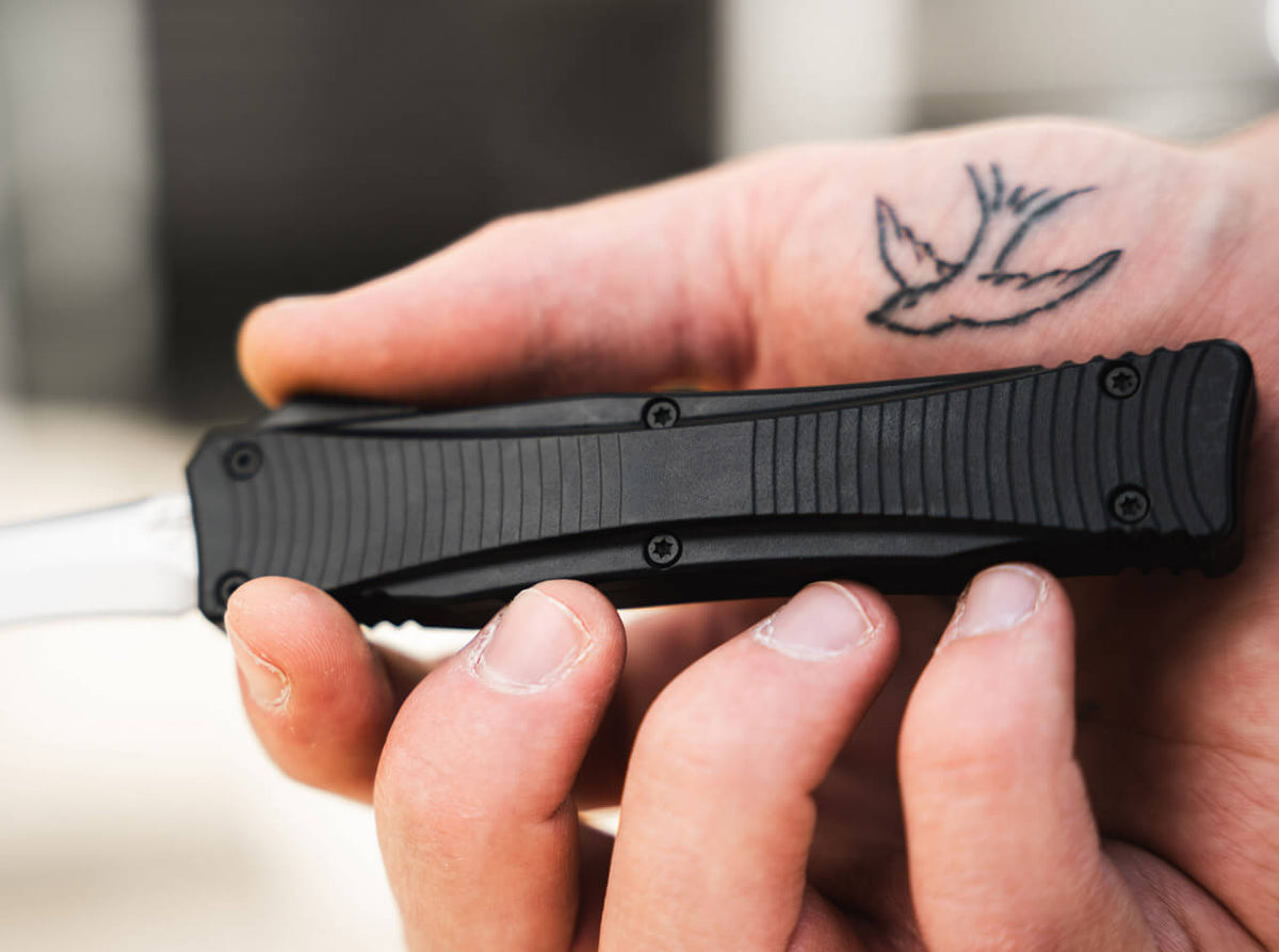 Grooved black aluminum handle of the Böker Plus Eagle 2.0 OTF knife held in hand