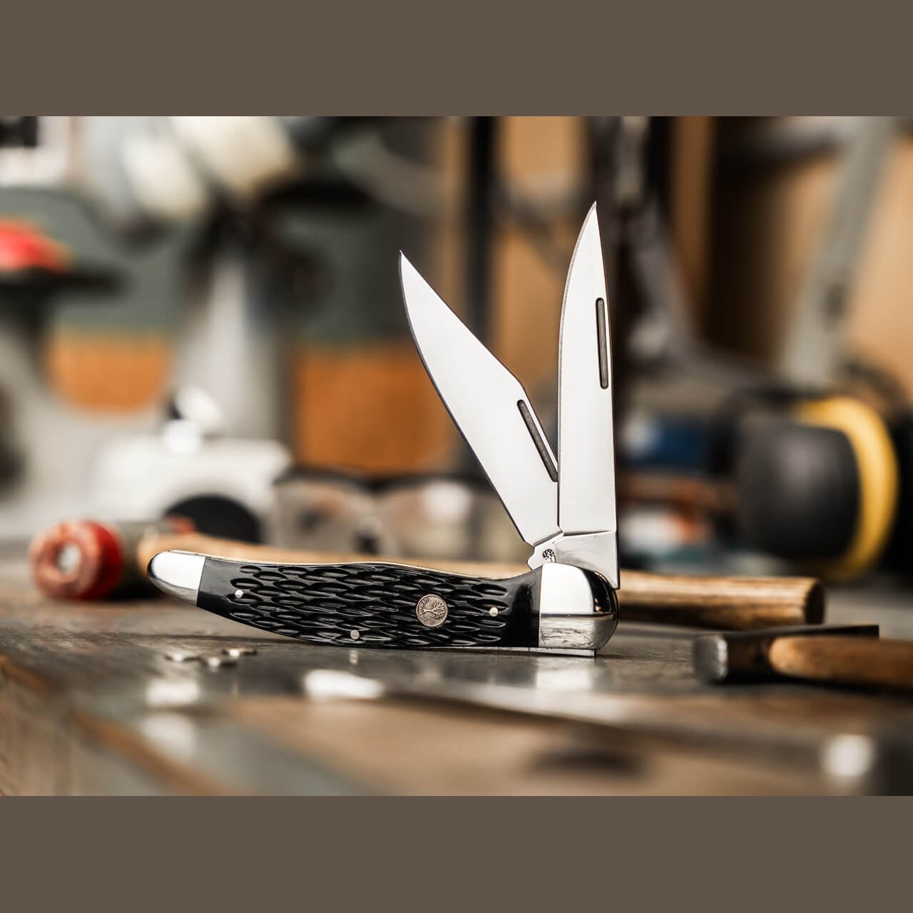 Boker Treebrand 1095 Folding Hunter with both blades open on a wooden workbench beside shop tools