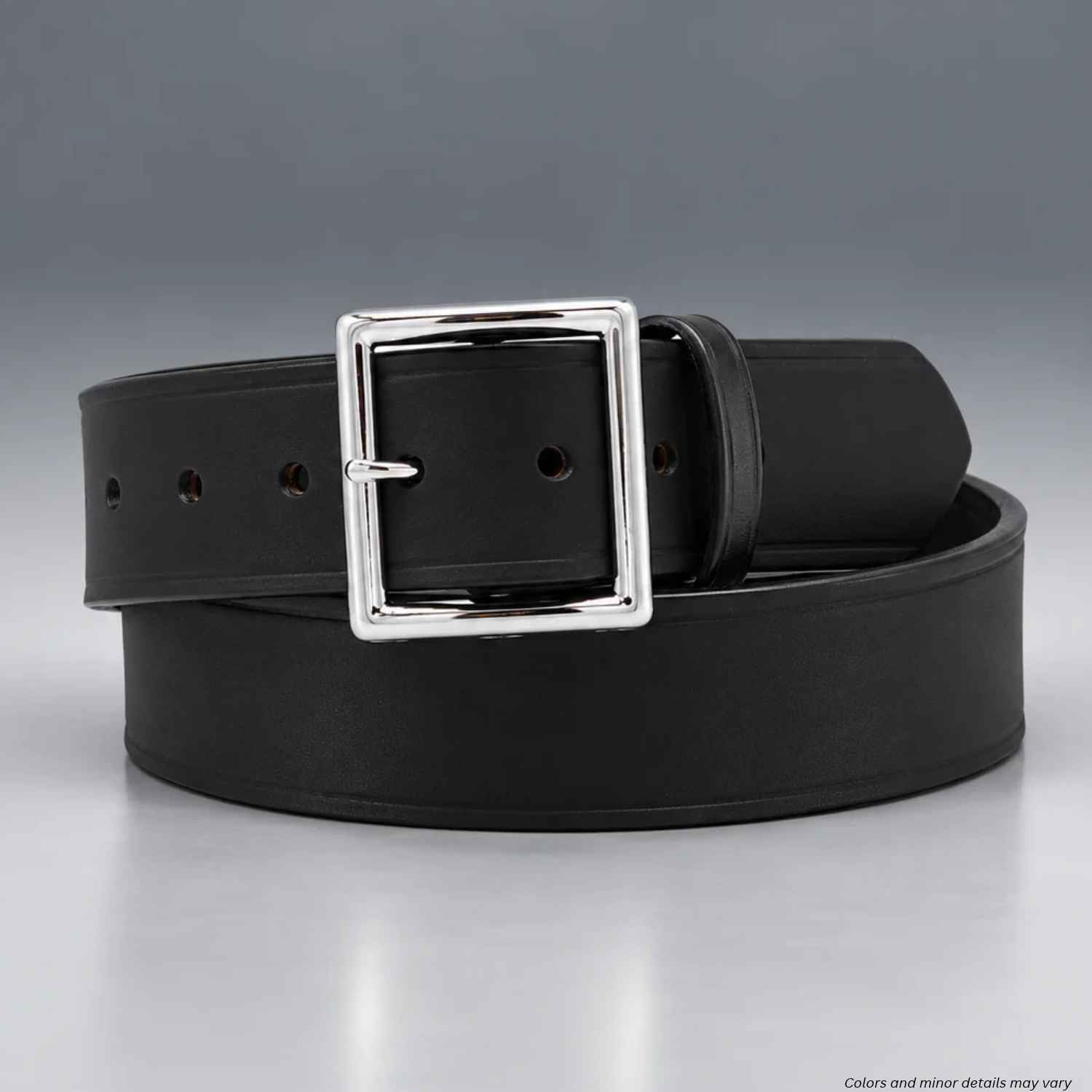 A black leather belt with a polished silver-tone square buckle, coiled on a reflective gray surface.